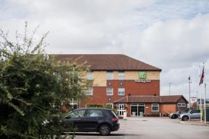 a building with a car parked in a parking lot at Holiday Inn Manchester West by IHG in Manchester
