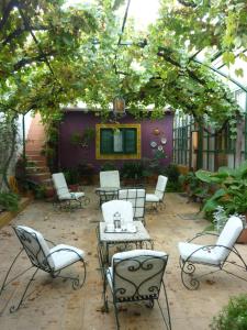 a patio with white chairs and a table and chairs at Hotel Mallorca in Mendoza