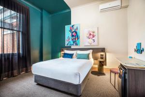 1 dormitorio con cama y pared azul en Ramsgate Hotel by Nightcap Social en Adelaida