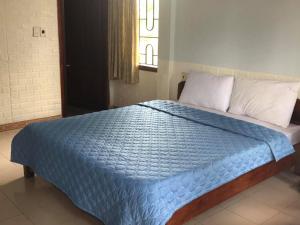 Quang TriにあるPALM GARDEN HOUSEのベッド(青い掛け布団付)、窓が備わります。
