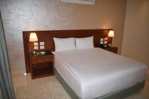 a bedroom with a bed with two night stands and two lamps at Omar El Khayam Al Minya Hotel in Al Minya