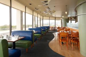 a dining room with tables and chairs and windows at Port Royal Oceanfront Hotel in Wildwood Crest
