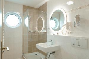 a bathroom with a sink and a shower with two windows at Hotel Glückauf 1908 in Ostseebad Sellin