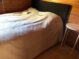 a bed in a room with a table and a stool at Three Rooms stuga i stugby near National Park in Undenäs