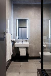 a bathroom with a sink and a mirror and a toilet at The Capital Melrose in Johannesburg