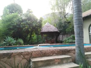 a swimming pool with a gazebo next to a house at Harties Double Bed 2 Sleeper Room with Shower in Hartbeespoort