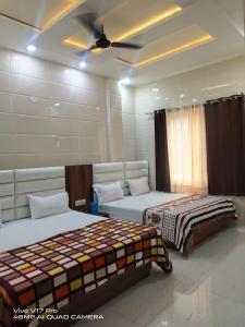 een slaapkamer met 2 bedden en een plafondventilator bij Jasneet Homestay in Amritsar