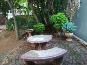 een stenen tafel en banken in de tuin bij Harties 2 Sleeper Double Room with Private Bathroom in Hartbeespoort