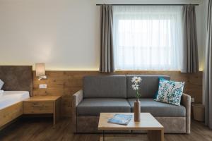 ein Hotelzimmer mit einem Sofa, einem Bett und einem Tisch in der Unterkunft Apparthotel Zunneler in Schenna
