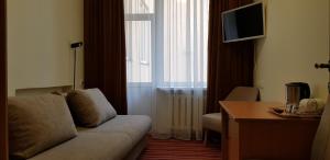 a living room with a couch and a desk and a television at Hotel Dainava in Druskininkai