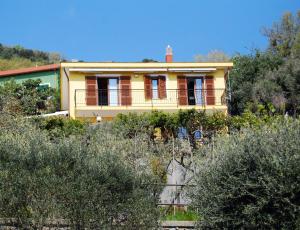 a yellow house on a hill with trees at Casa Bellavista in Bergeggi