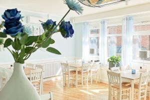 a room with tables and chairs and a vase with blue flowers at Hotel Restaurant Haus Korfu in Anholt