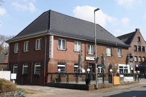 a red brick building with a black roof at Hotel Restaurant Haus Korfu in Anholt