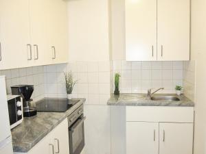 una cocina con armarios blancos y fregadero en SUNNYHOME Monteurwohnungen und Apartments in Weiden en Weiden