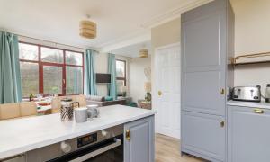 a kitchen with white countertops and a living room at Gorgeous cottage by sandy beach Dog friendly in Port Erin