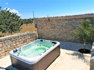 uma banheira de hidromassagem num pátio ao lado de uma parede de tijolos em Il Baglio di Kharrub rural guest house em Pozzallo