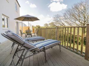 two lounge chairs and an umbrella on a deck at Trevena in Tintagel