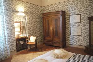 a bedroom with a bed and a cabinet and a desk at Camera Suite Romantica con Giardino in Dimora Storica - B&B Palazzo Robicci in Castiglion Fiorentino