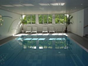 a room with a pool with chairs and windows at Wellness Ferienwohnung Schweinsteiger mit Hallenbad und Sauna in Oberaudorf