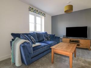 a living room with a blue couch and a tv at Trevena in Tintagel