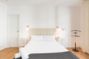 un letto bianco in una camera da letto bianca con pareti bianche di Urbe10 Plaza de la Constitucion 1 Bedroom Apartment a Málaga