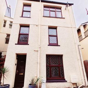 ein weißes Backsteingebäude mit Fenstern und einer Tür in der Unterkunft Gorgeous cottage by sandy beach Dog friendly in Port Erin