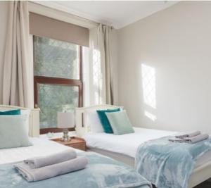 ein weißes Zimmer mit zwei Betten und einem Fenster in der Unterkunft Gorgeous cottage by sandy beach Dog friendly in Port Erin