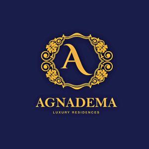 a letter in a gold ornamented circle logo at AGNADEMA Luxury Residences in Schinoussa
