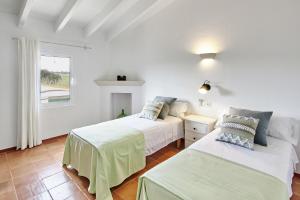 two beds in a white room with a window at Son Camaro in Ciutadella