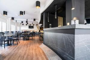 un ristorante con un bar con tavoli e sedie di Abasto Hotel München Feldmoching a Monaco