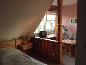 a bedroom with a bed and a desk and a window at Pension An der Bleiche in Wustrau