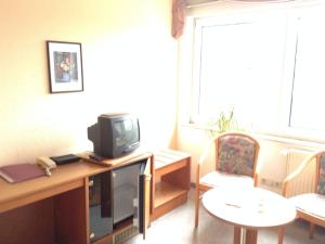 a living room with a tv and a table and chairs at Pension An der Bleiche in Wustrau