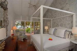 a bedroom with a white canopy bed and a patio at Sugar Reef Bequia - Adults Only in Crescent Beach