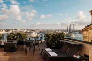 a balcony with tables and chairs and a view of a city at 1926 Le Parisot Boutique Suites in Valletta