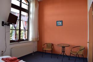 Zimmer mit einem Tisch, 2 Stühlen und einem Fenster in der Unterkunft Pension zur Alten Schule in Kirchberg