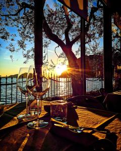 a table with wine glasses on it with the sunset at La Foresta Monteisola in Monte Isola