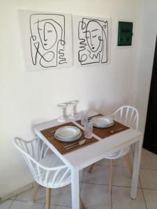 Santo Spiti sou 6 في فيرا: طاولة غرفة طعام بيضاء مع كرسيين بيض