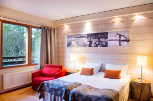a bedroom with a bed and a red chair at Lapland Hotels Riekonlinna in Saariselka +48 photos