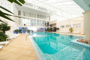 a large swimming pool in a building with white chairs at Морський in Odesa
