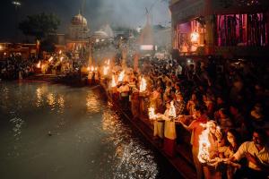 uma multidão de pessoas em pé ao lado de um rio com luzes em Ganga Heritage By Howard em Haridwār