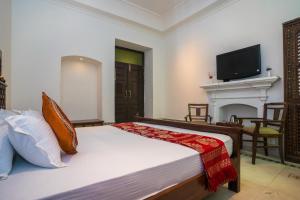 a bedroom with a bed with a fireplace and a tv at Ganga Heritage - By The Palm Bliss Resort in Haridwār