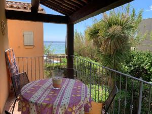 a table with a drink on a balcony with the ocean at Au bord de la mer in Cavalaire-sur-Mer