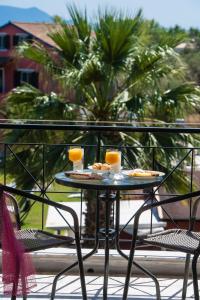 リジアにあるArtemis Pension by Imagine Lefkadaのテーブル(椅子2脚付)とオレンジジュース2杯