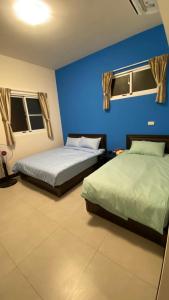 - 2 lits dans une chambre avec un mur bleu dans l'établissement Murakami Travel Guest House, à Huxi