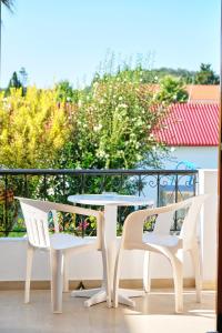three white chairs and a table on a balcony at Tria Adelphia in Arillas