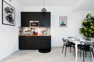 una cocina con armarios negros y una mesa con sillas en Apartament Solny Centrum Wieliczka 11, en Wieliczka