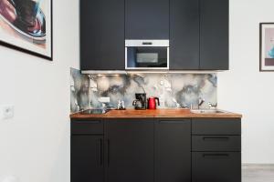 a kitchen with black cabinets and a microwave at Apartament Solny Centrum Wieliczka 11 in Wieliczka +19 photos