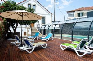 un groupe de chaises et un parasol sur une terrasse dans l'établissement Hotel Solar do Rebolo, à Oliveira do Hospital