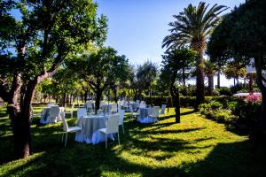 a group of tables with white chairs and trees at Hotel Alpha in Sant'Agnello