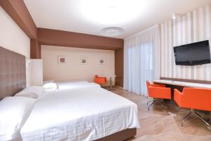 a bedroom with a bed and a desk and a television at Bhotel in Lagonegro